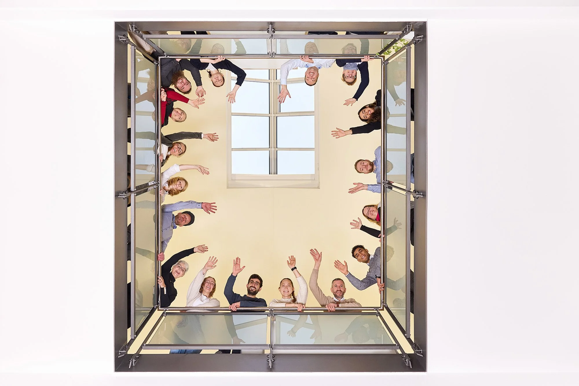 Eine Gruppe Mitarbeiter schaut winkend die Empore hinunter zum Werbefotografen in Leipzig