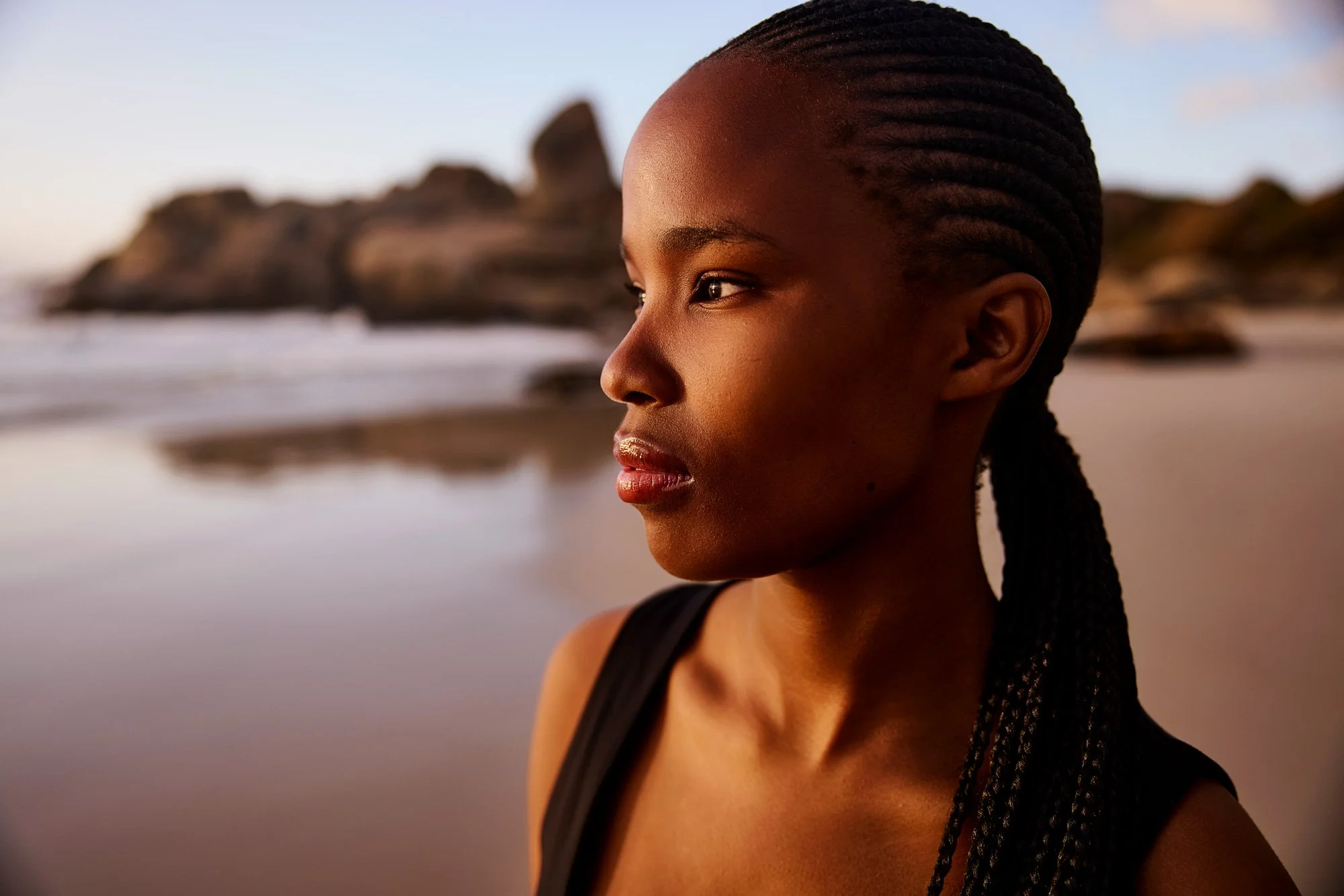 Eine Nahaufnahme von einer jungen Frau, die am Strand nachdenklichen Sonnenlicht schaut