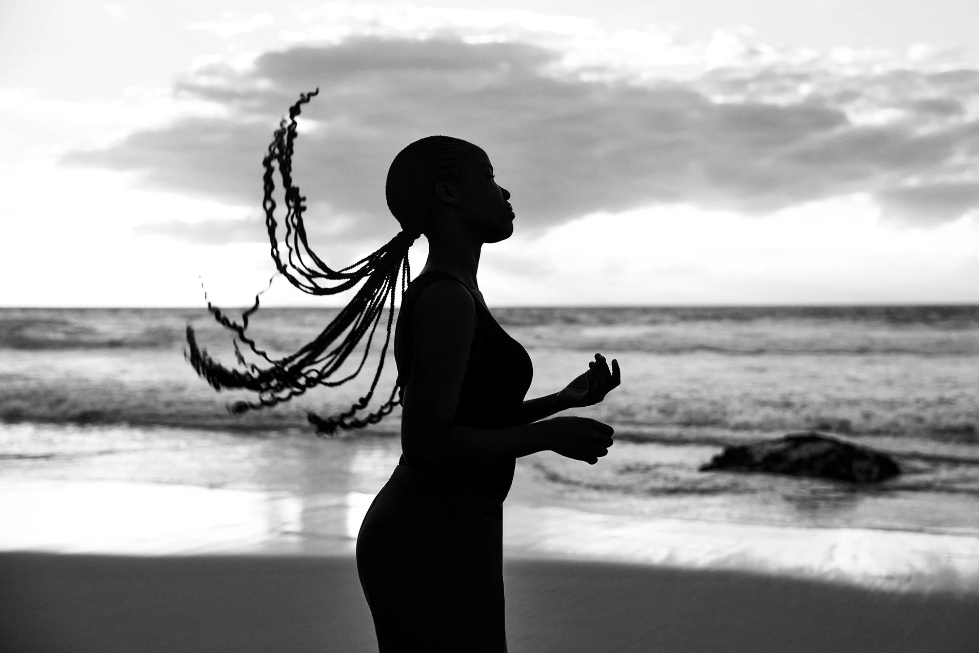 Eine Frau wirft ihre Haare im Gegenlicht zurück auf einem schwarz-weiß Foto