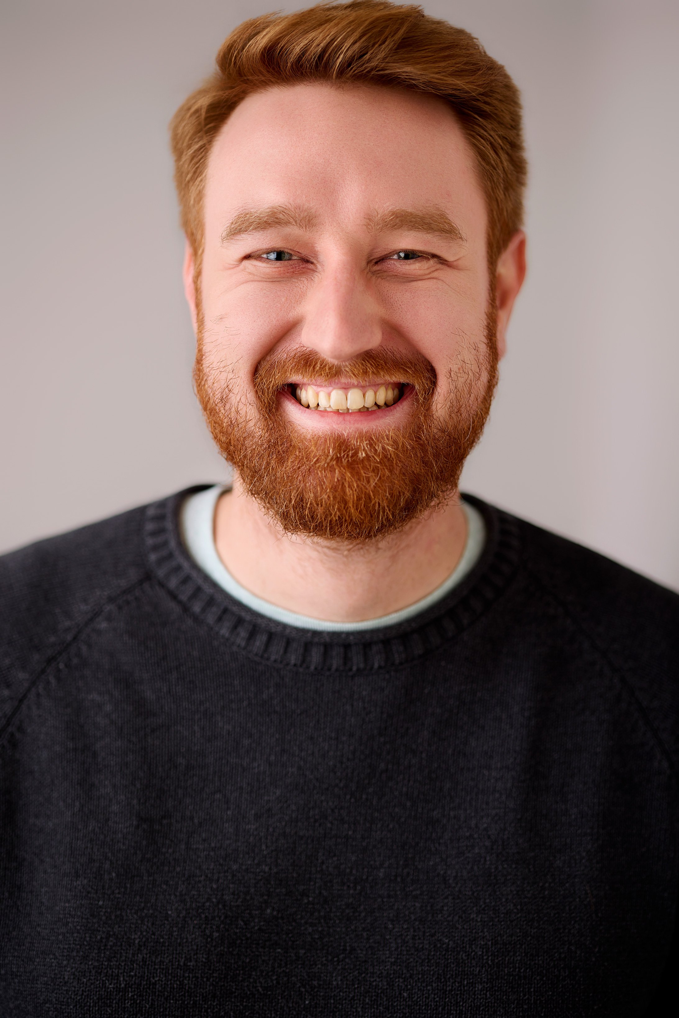 Ein Mann mit Bart strahlt  frontal in die Kamera