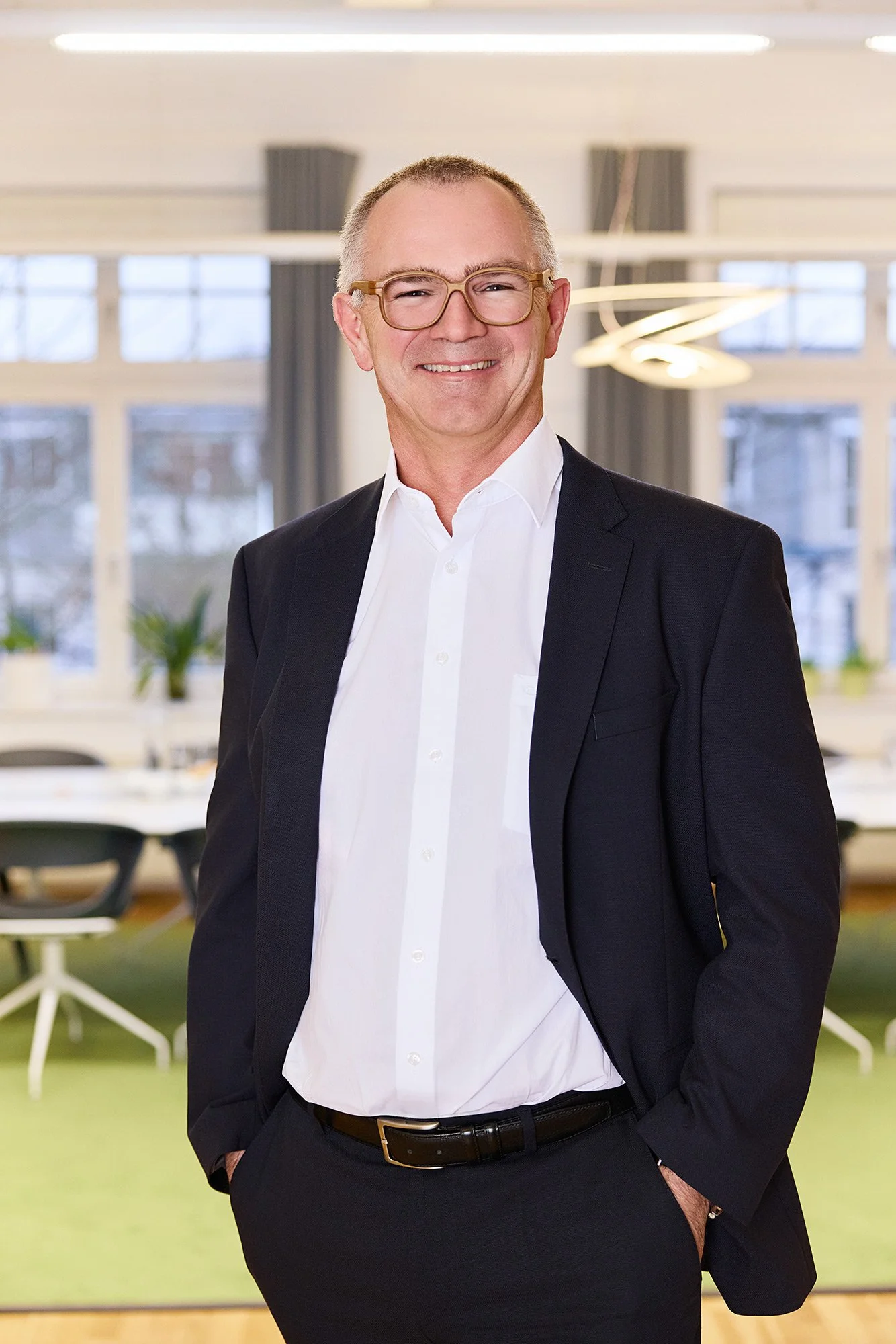 Ein Mann mit Brille lächelt für sein Mitarbeiterfoto in Leipzig in die Kamera