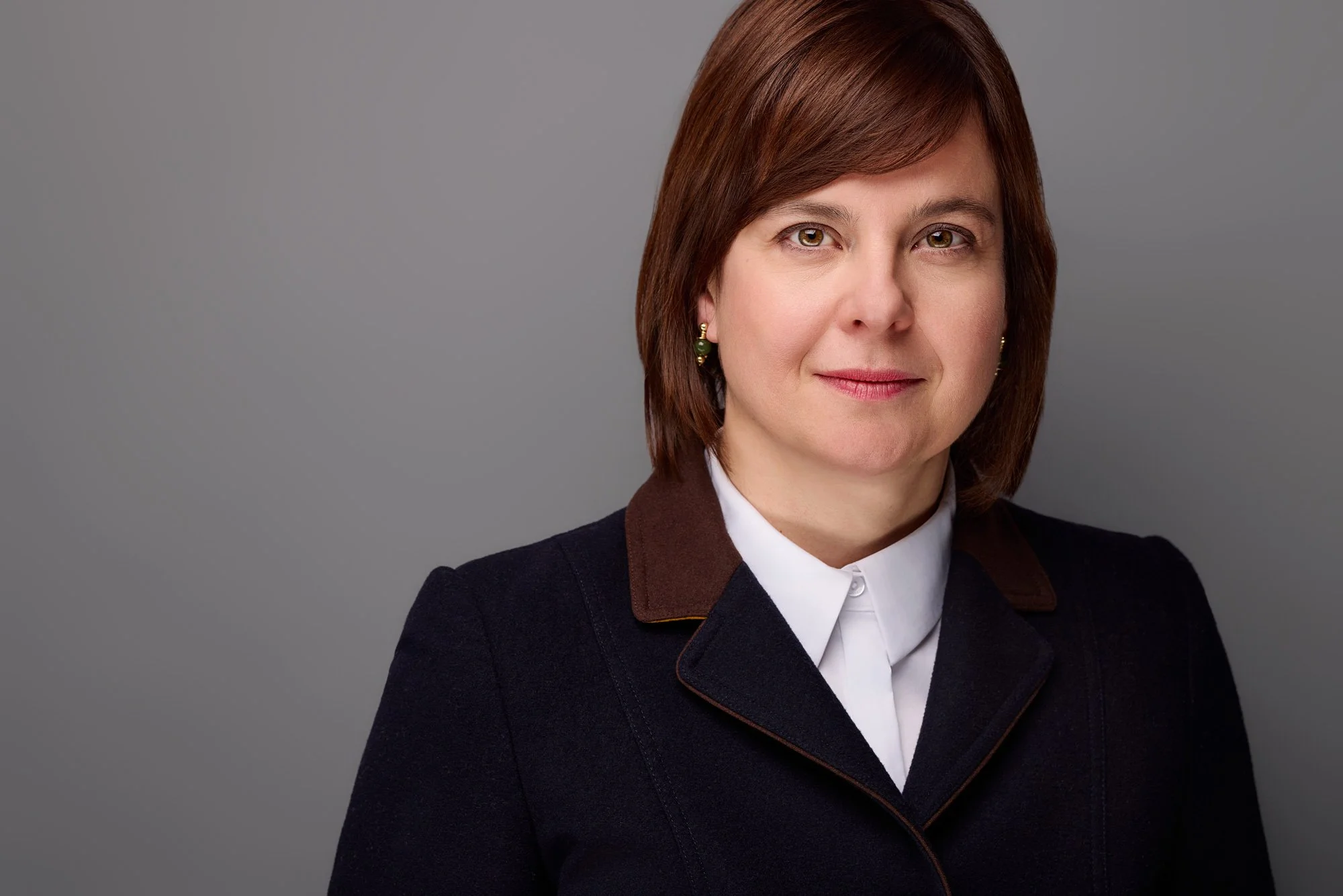 Eine Frau mit gepflegten Aussehen und dunklen Haaren  schaut in die Kamera posiert für ihre Bewerbungsfotos