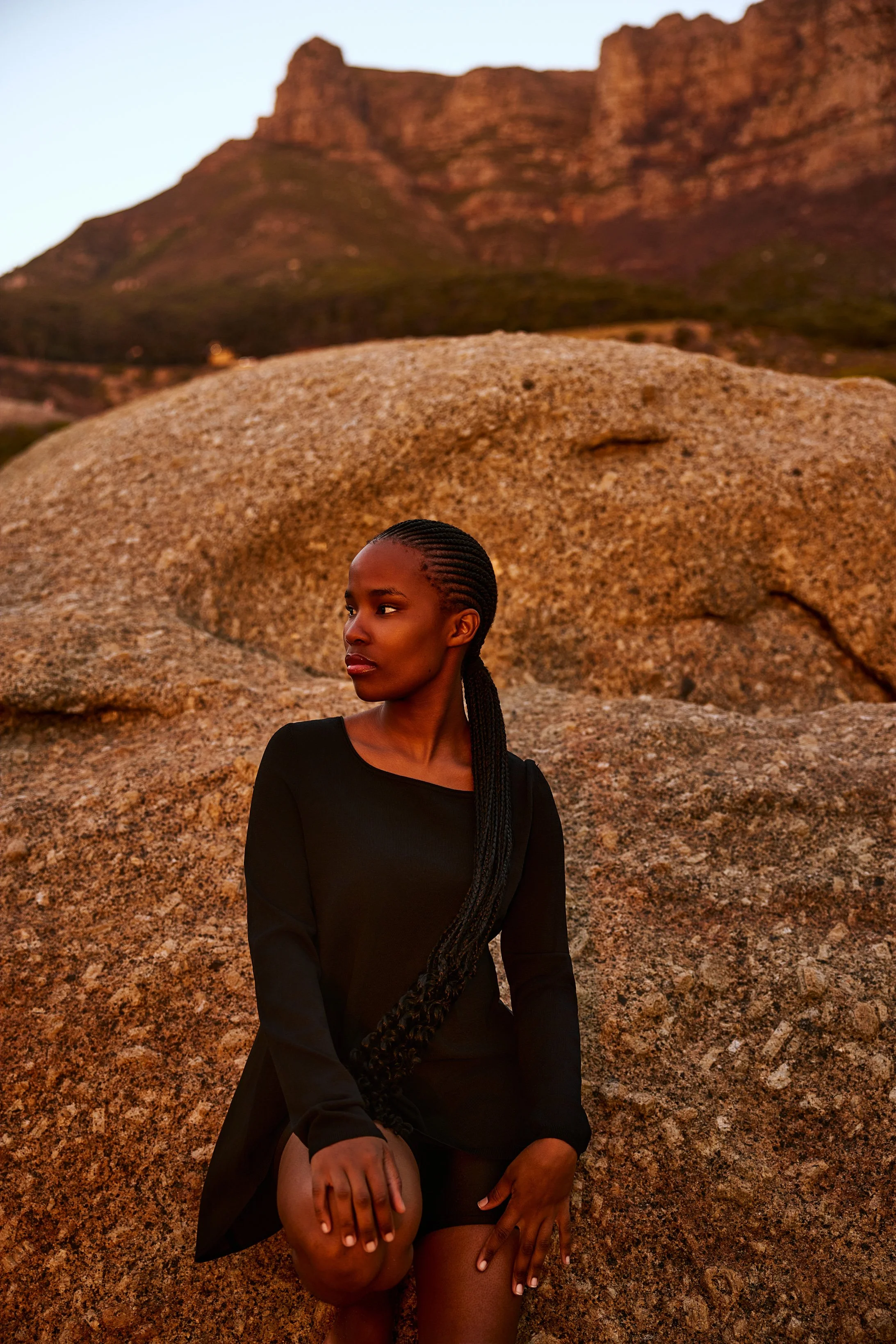 Ein Portraitfoto von einer jungen Frau, die an einem Felsen angelehnt ist