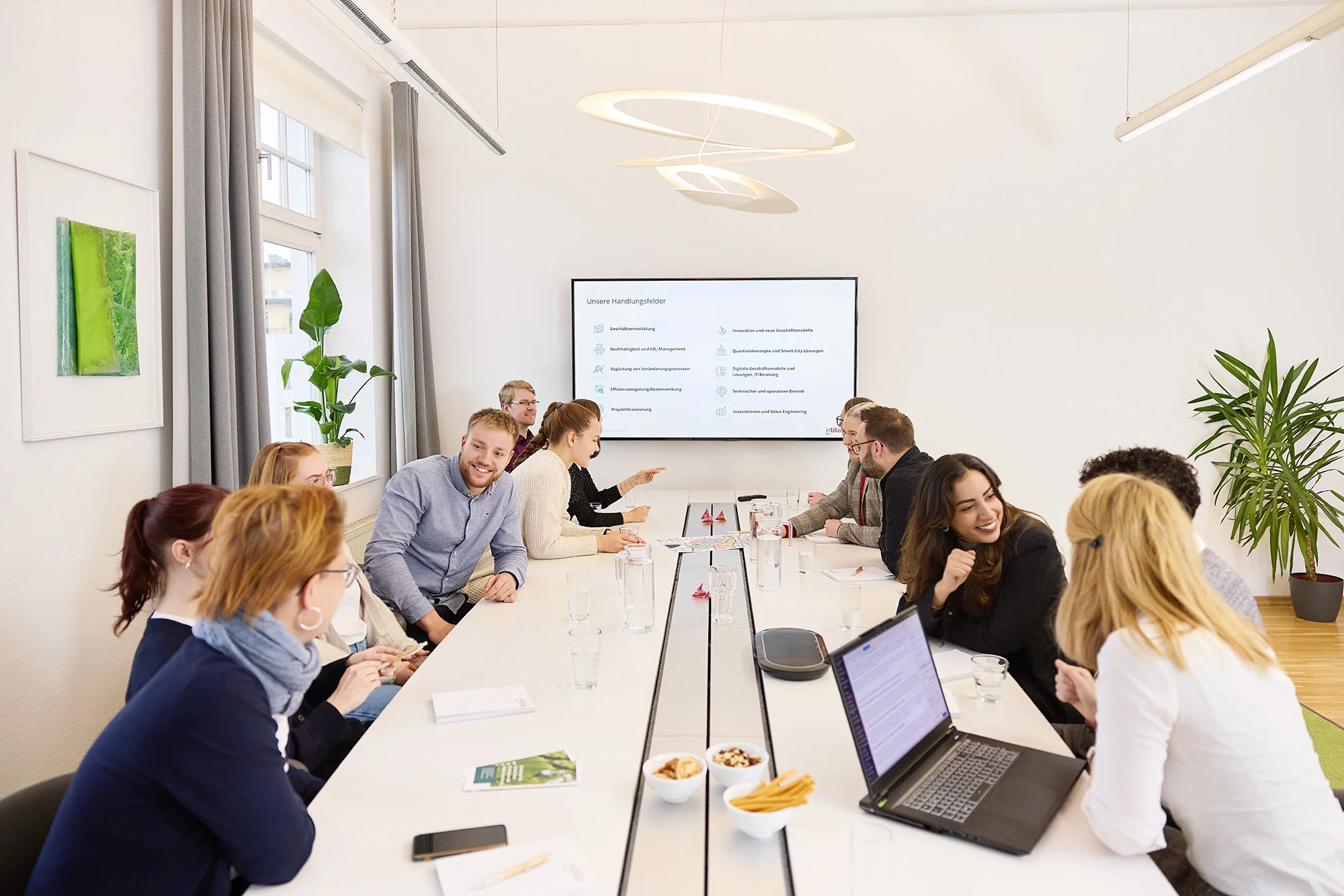 Eine große Gruppe Mitarbeiter sitzt in einem Besprechungsraum am Besprechungstisch