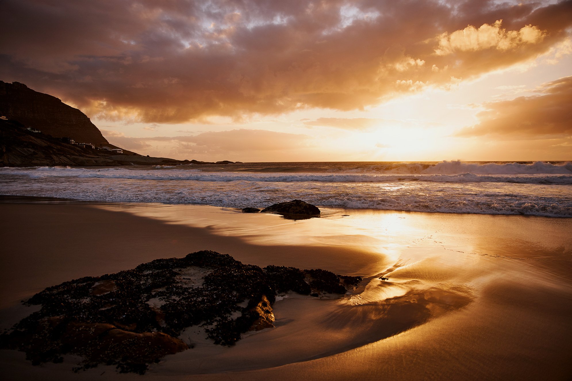 Eine Aufnahme vom Meer von einem Strand in Kapstadt bei Sonnenuntergang