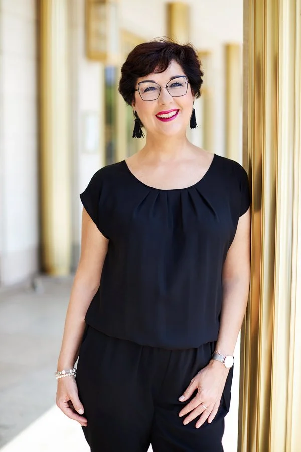 Eine Frau mit dunkle Kleidung lehnt an einer goldenen Säule für Ihr Business Portrait