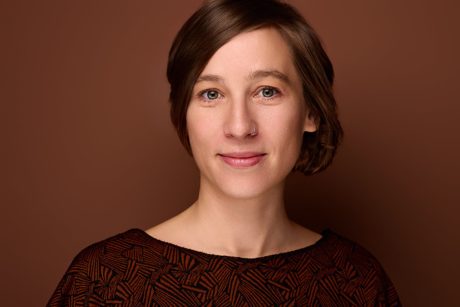 Eine Frau steht vor einem braunen Hintergrund und lächelt in die Kamera für den Fotografen in Leipzig