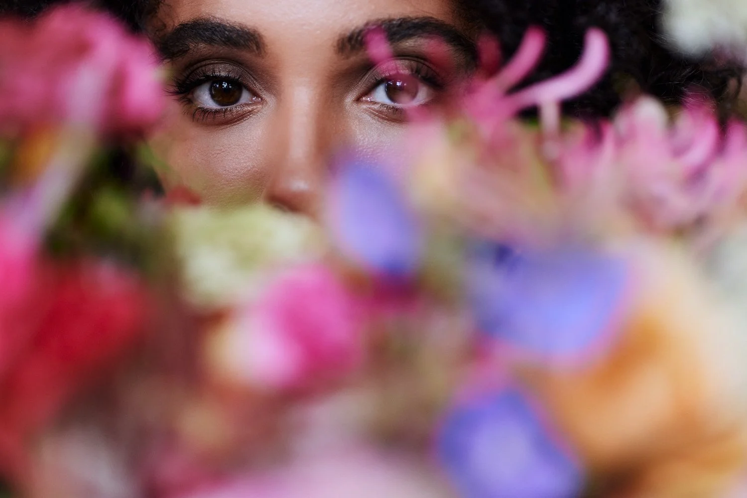 Eine Frau schaut mit den Augen über einen Blumenstrauß