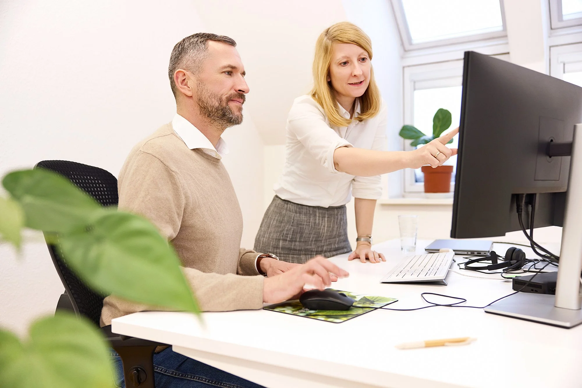 Eine Kollegin zeigt einem Mitarbeiter etwas am Bildschirm