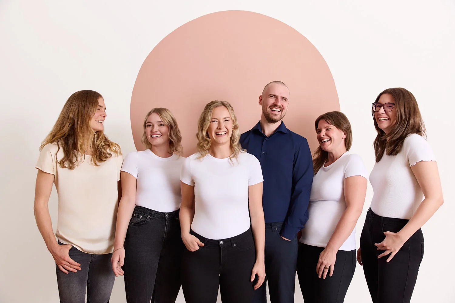 Ein Team Foto von einer Arztpraxis in dem Mitarbeiter zusammen mit ihrer Ärztin lächelnd nebeneinander stehen