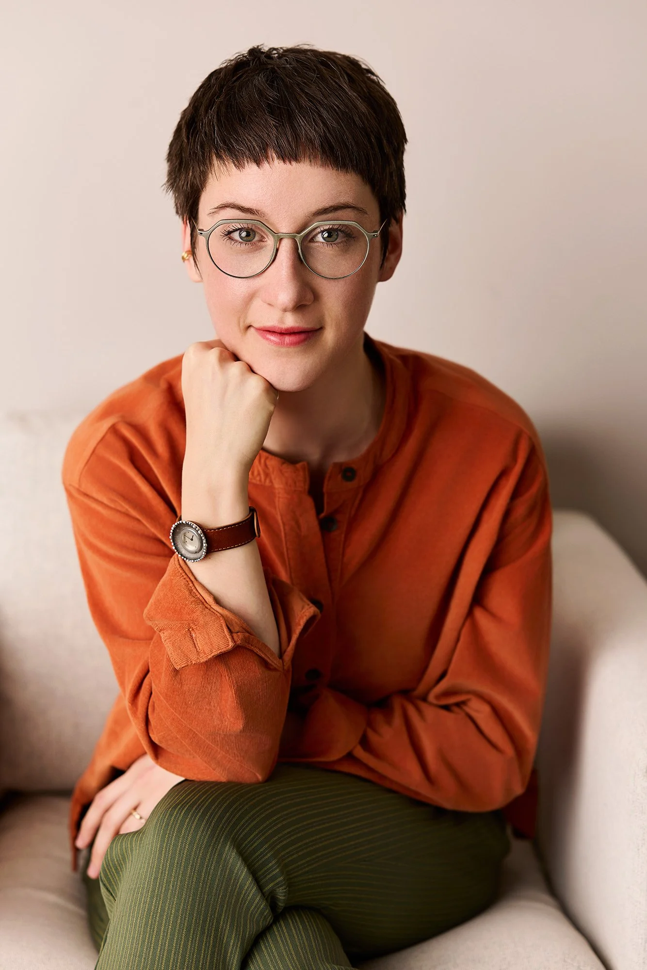 Eine Frau mit markanter Brille sitzt auf einem Sessel und schaut in die Kamera des leipziger Fotografen