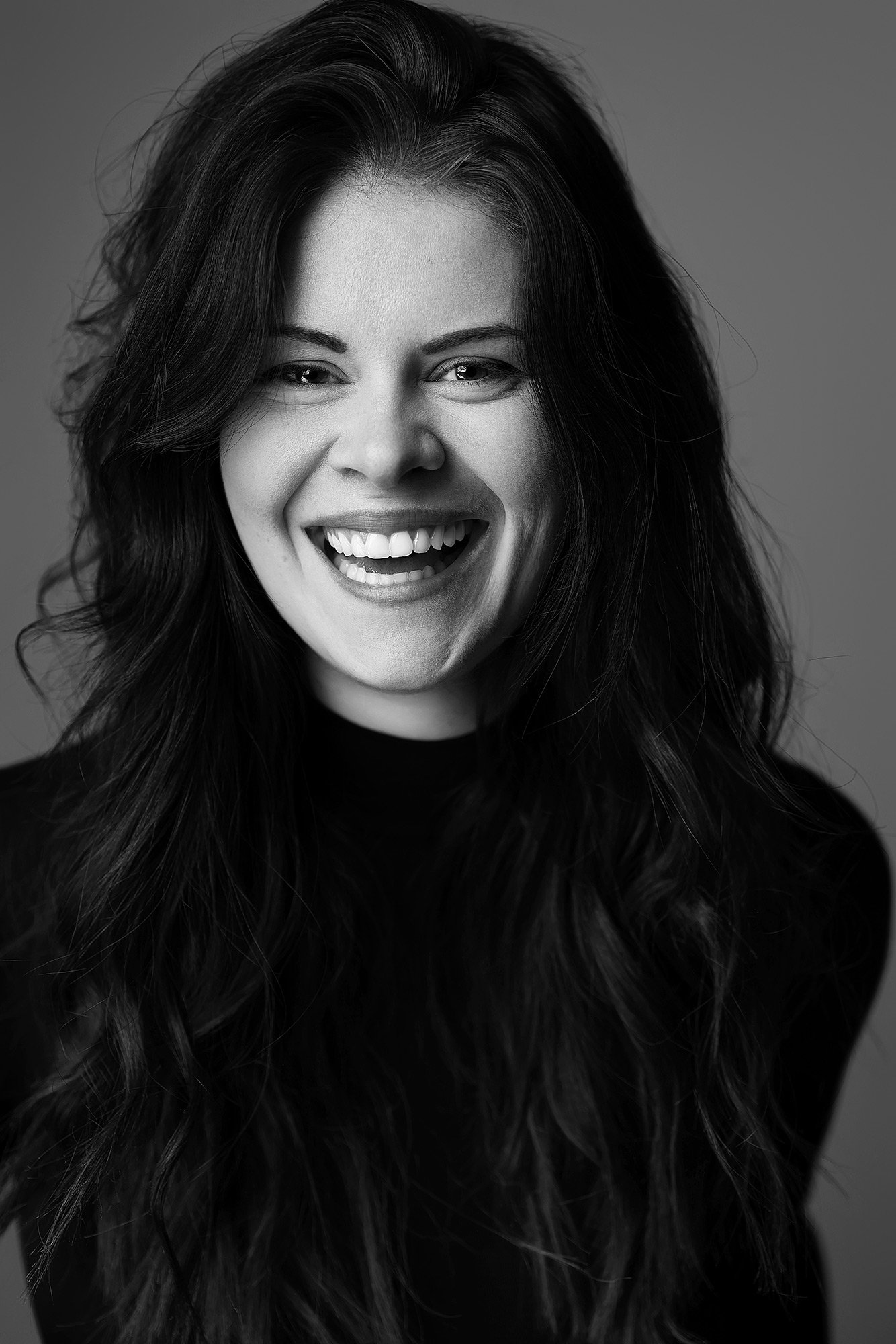 Eine dunkelhaarige Frau lacht in die Kamera