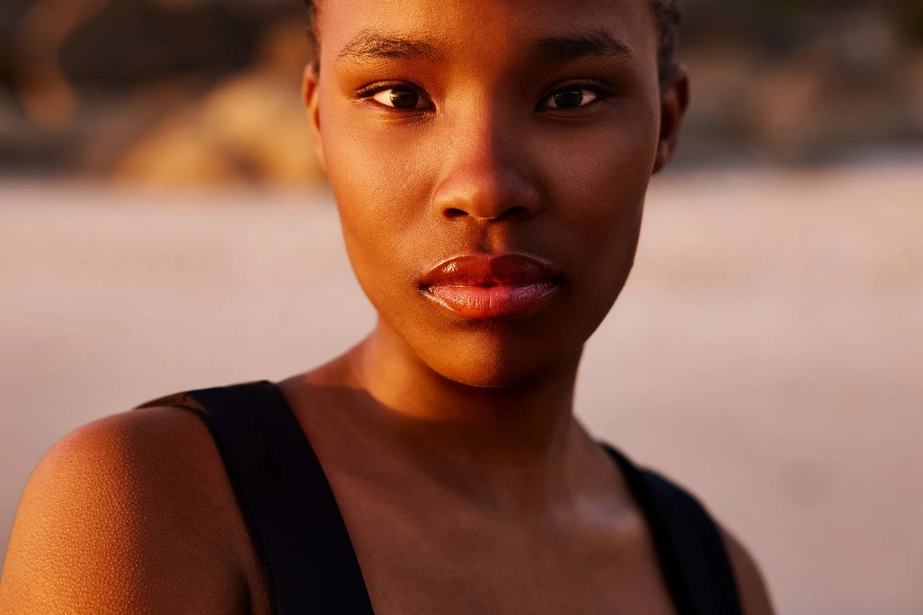 Eine junge Frau schaut direkt in die Kamera des Portrait Fotografen und wird vom Sonnenlicht angestrahlt