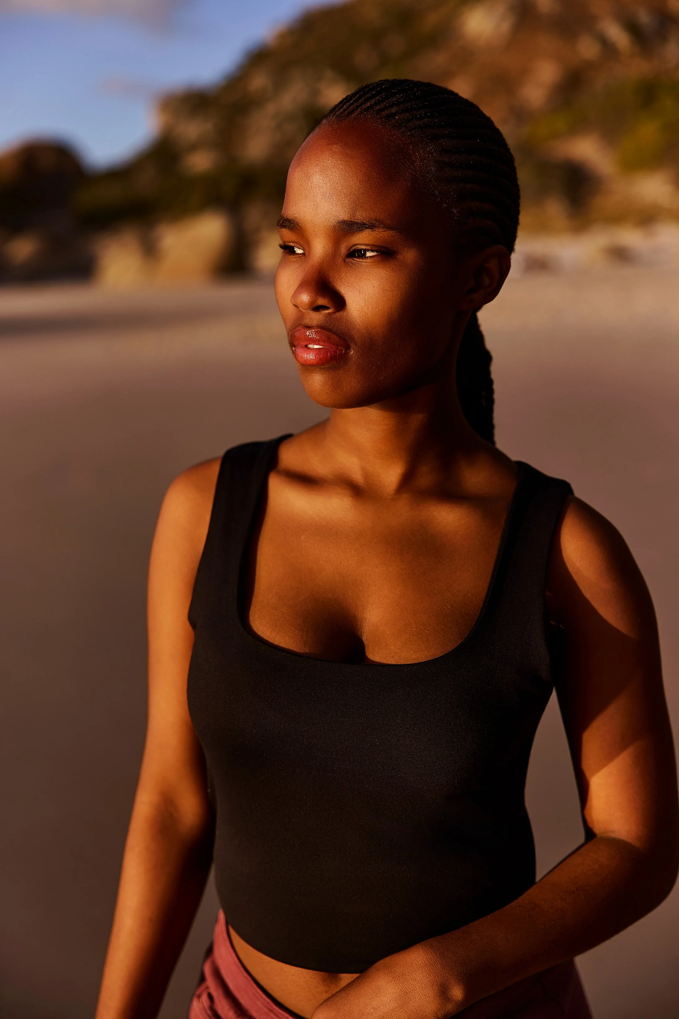 Eine junge Frau steht am Strand und schaut in die Sonne