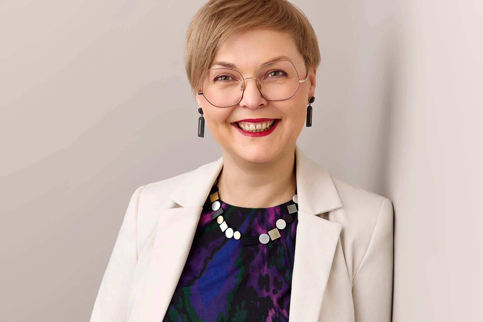 Eine Frau mit Brille lehnt an einer grauen Wand in einem Leipziger Fotostudio.