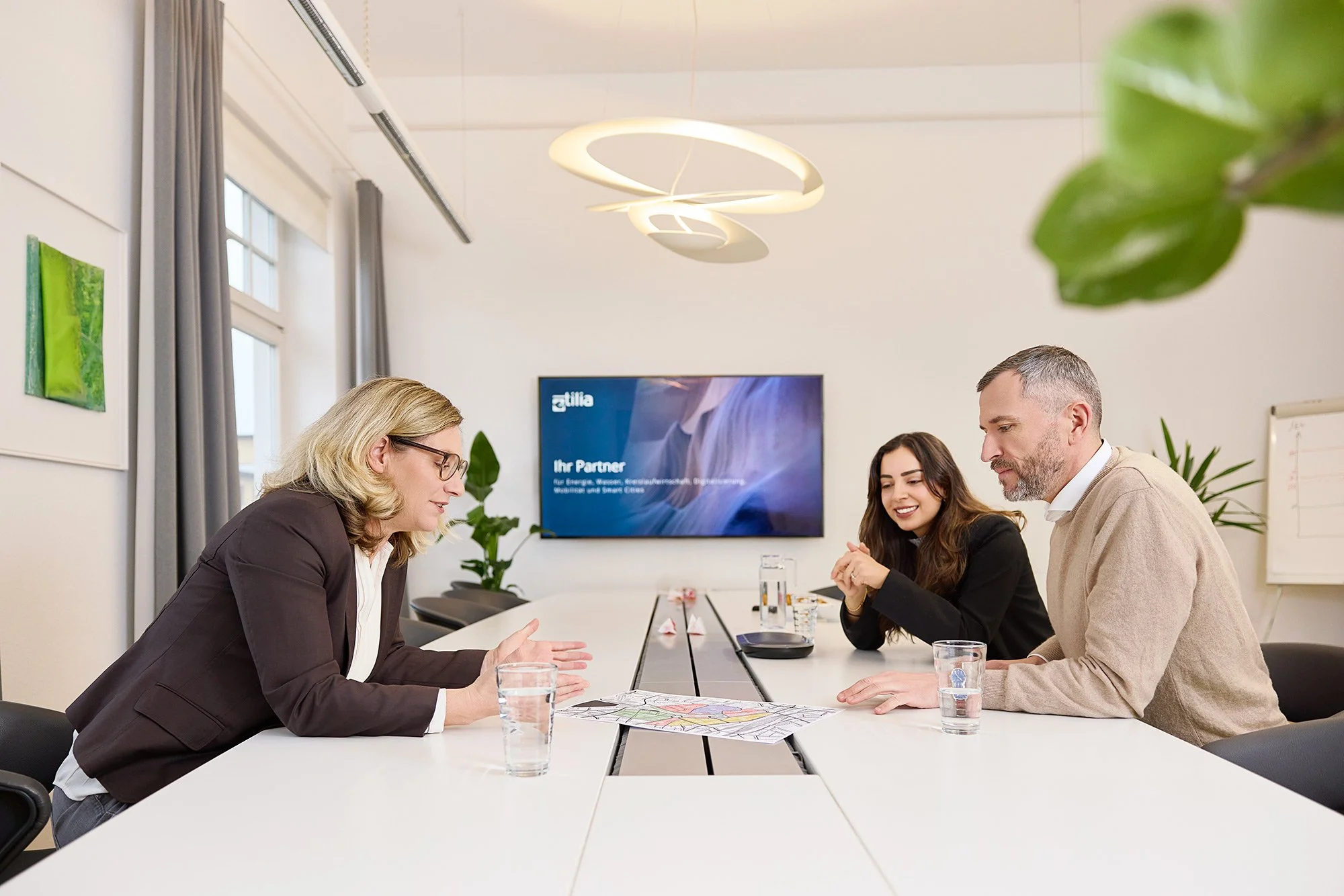 Drei Mitarbeiter einer Firma sitzen gemeinsam am Beratungstisch