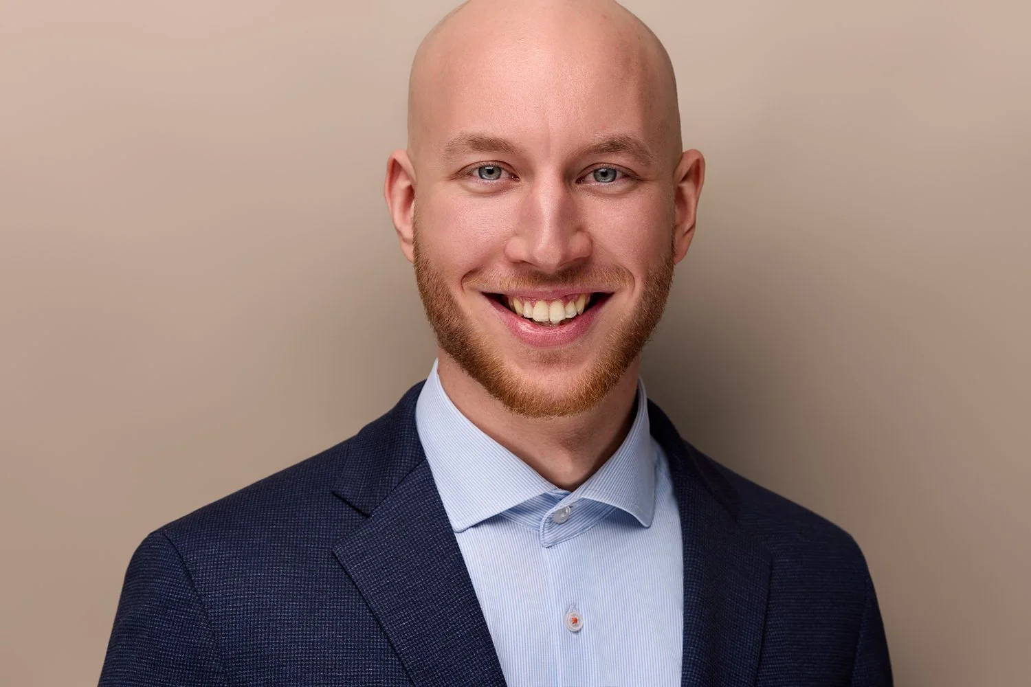 Ein Bewerbungsfoto von einem Mann mit Glatze, der die Kamera lächelt
