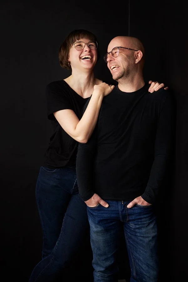 Ein Pärchen steht schwarz gekleidet vor einem schwarzen Hintergrund in einem Fotostudio in Leipzig