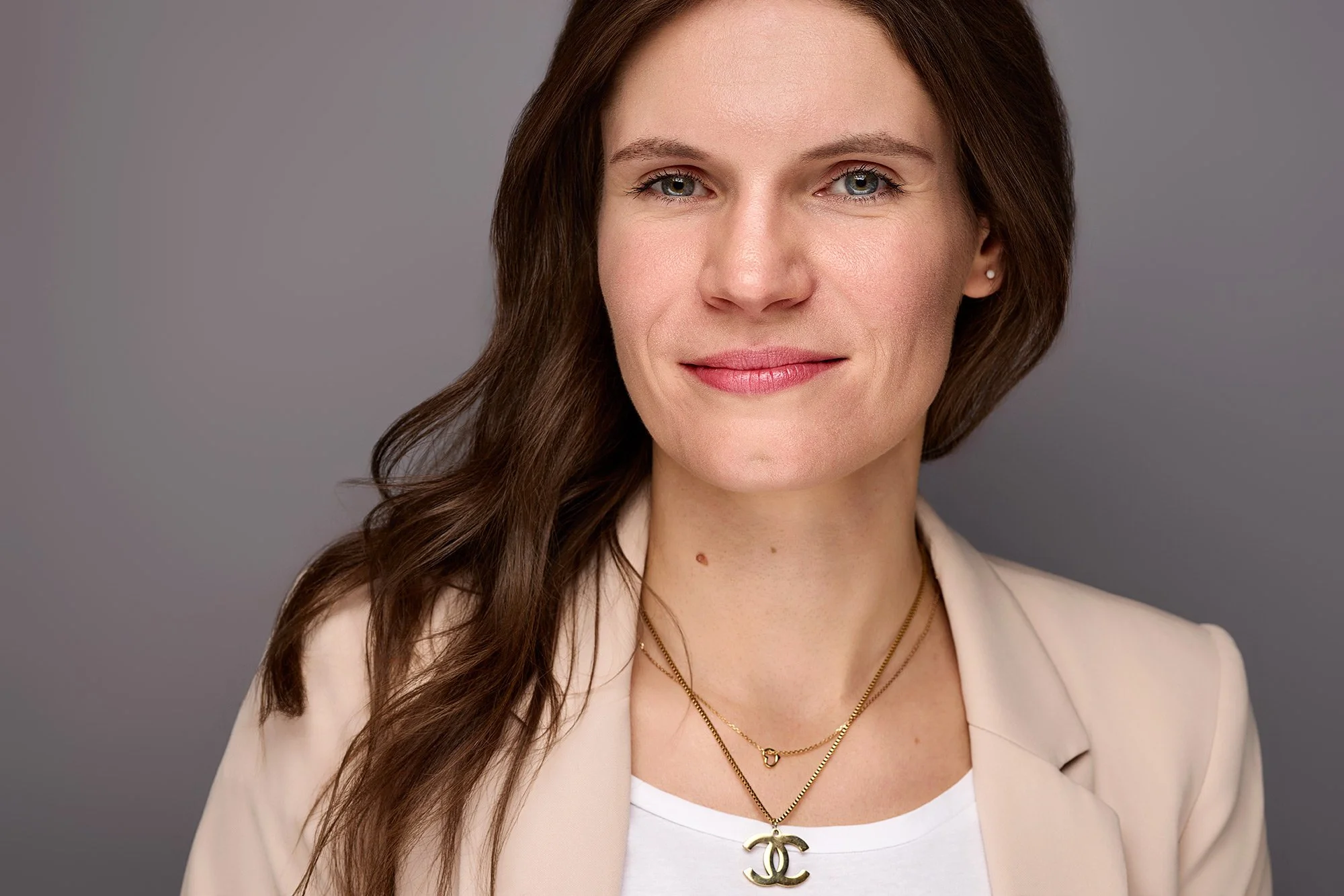 Ein Businessfoto von einer  Frau die vor einer grauen Wand in einem Fotostudio steht.