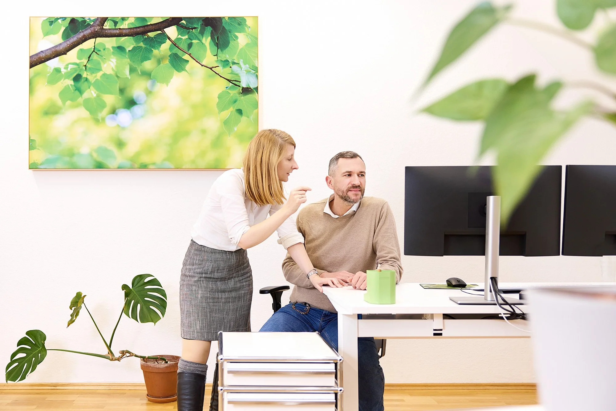 Eine Mitarbeiterin erklärt ihren Kollegen etwas am Computer