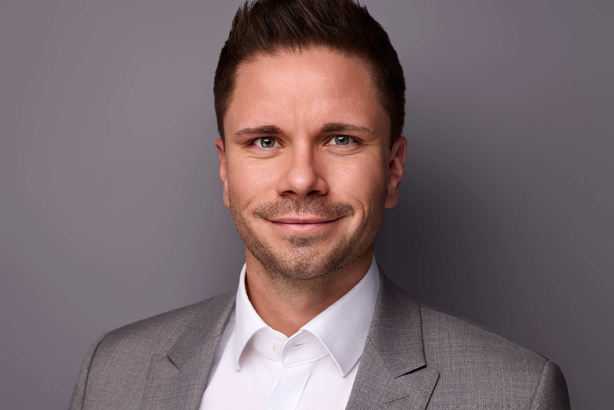 Businessfoto von einem Mann mit grauem Anzug vor grauem Hintergrund