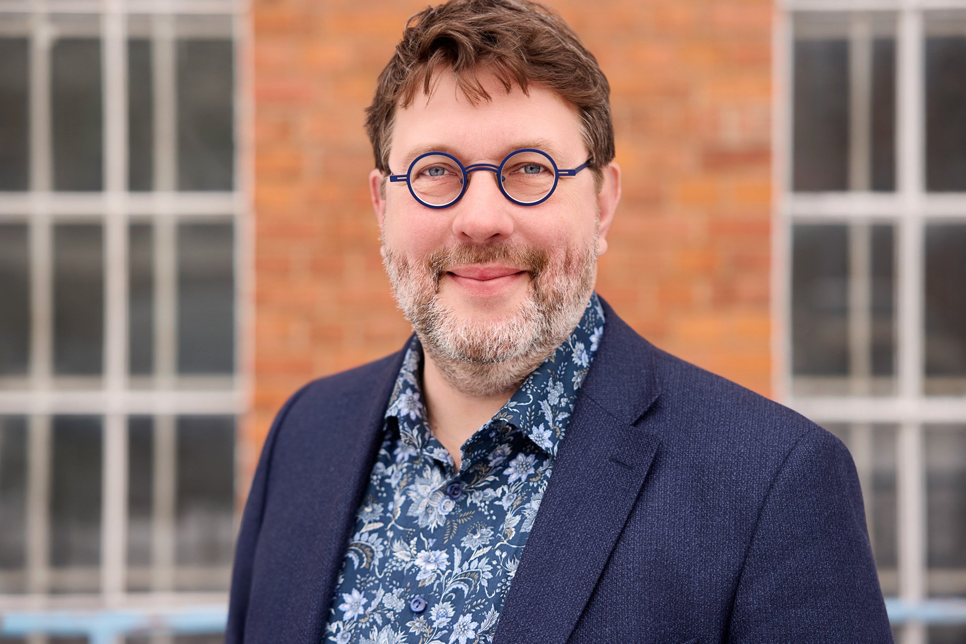 Ein Mann mit Bart und runder Brille posiert für sein LinkedIn Profilbild on Location in Leipzig