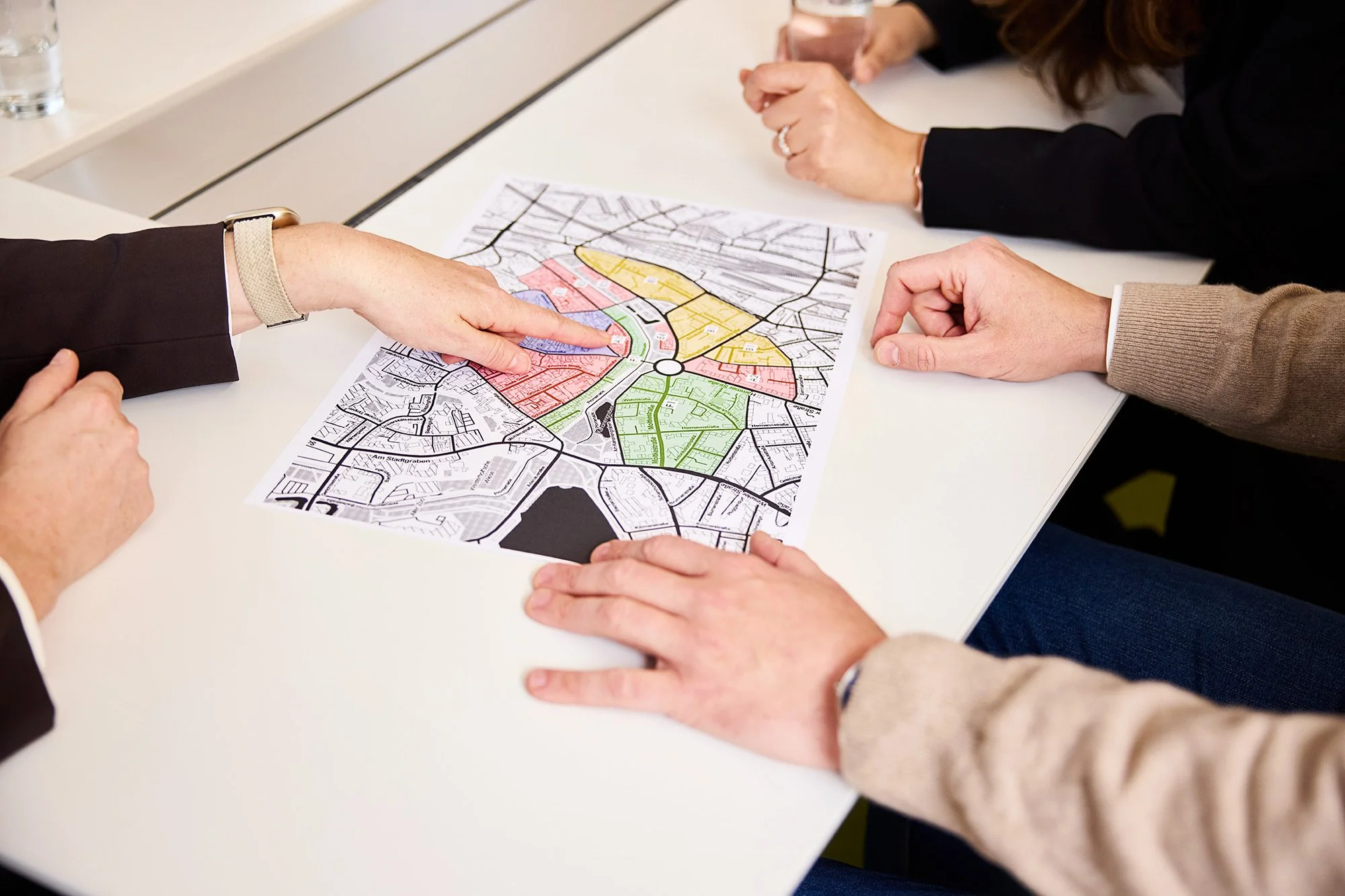 Eine Werbefotografie von einem Plan als Detail und Händen, die darauf etwas zeigen