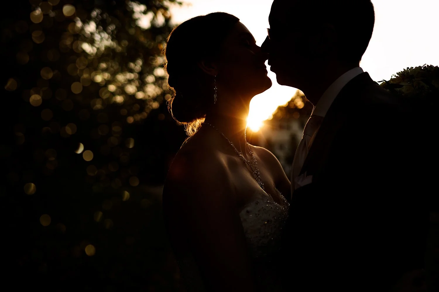Ein Scherenschnitt von einem Brautpaar, welches sich im Gegenlicht küsst