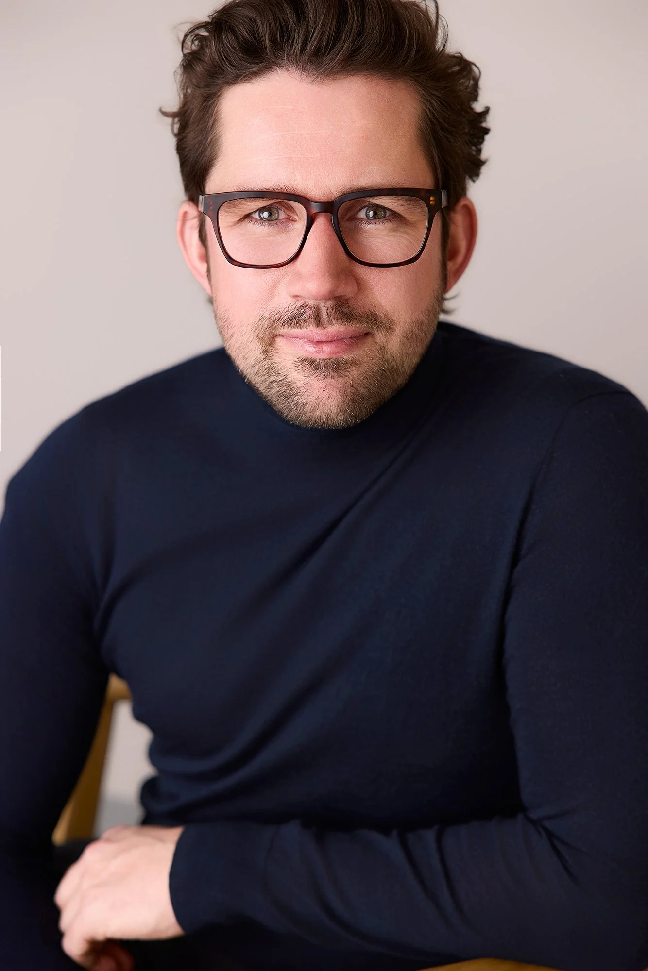 Ein Business-Portraitfoto von einem Mann mit Brille und dunklem Pullover