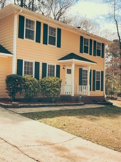 After. We thought the yellow house was cute, so we painted the shutters a dark blue and installed a new front door.