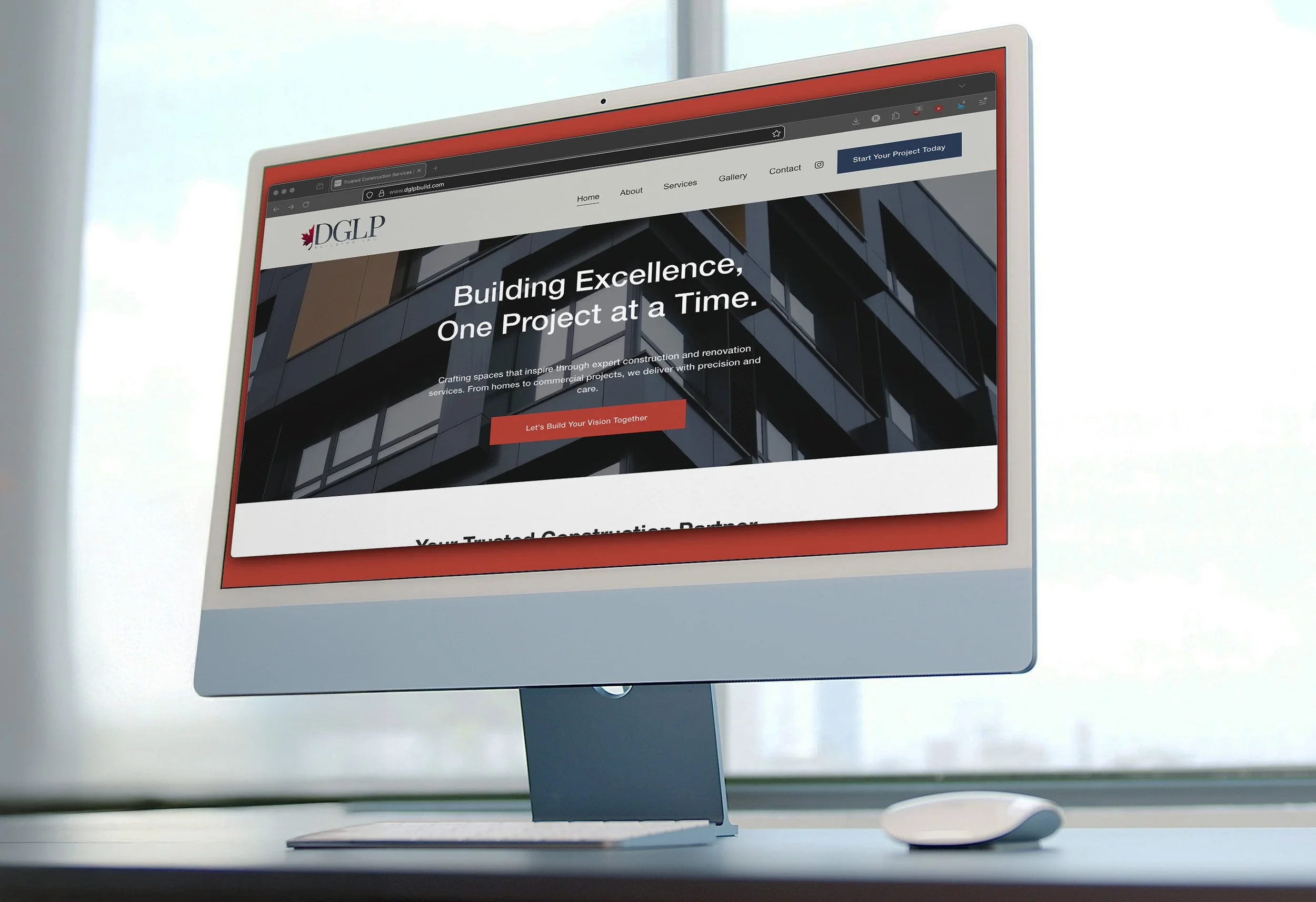 Computer monitor displaying a construction company's website on a bright desk near a window.