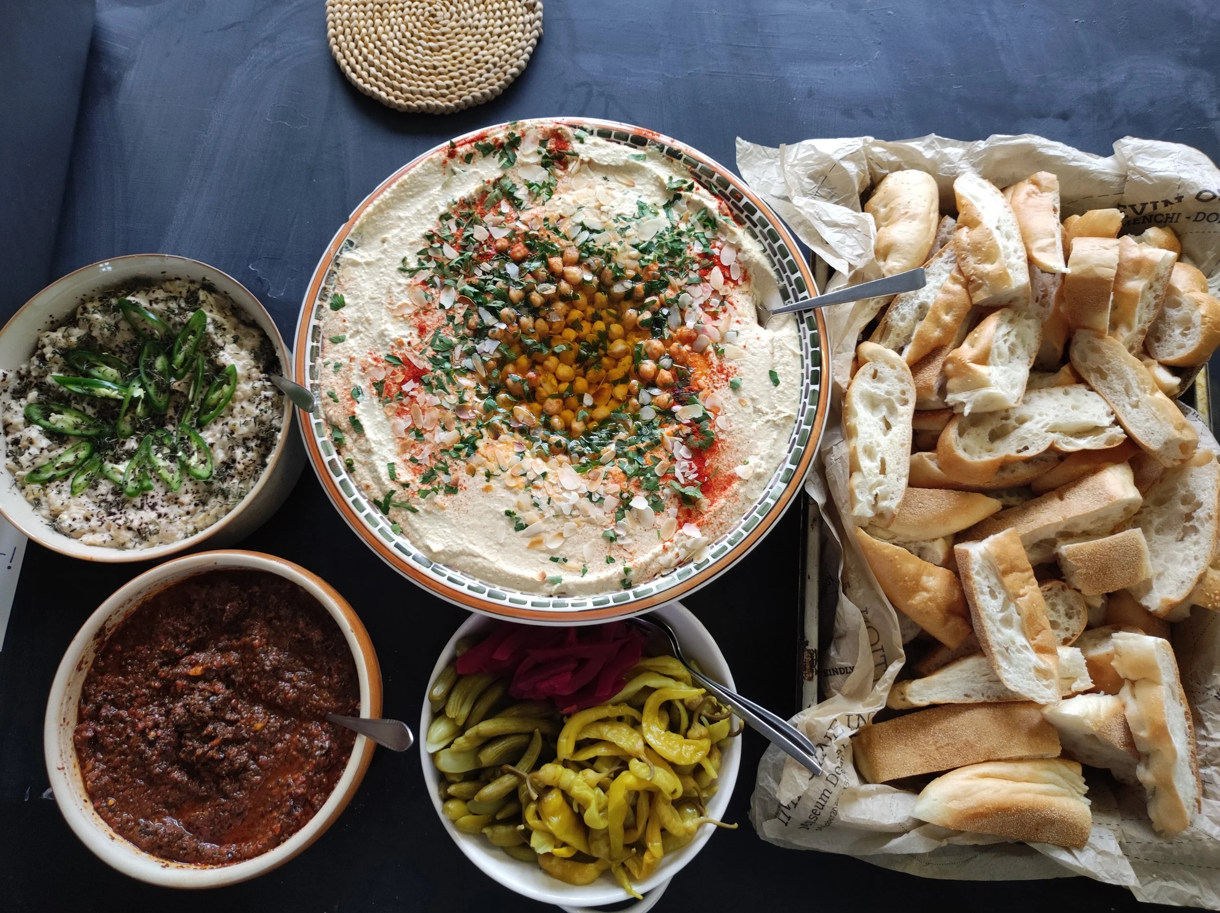 Brood met dips: humus, baba ganoesj met isot biber en tijm, en tomatentapenade met zwarte knoflook en arak.