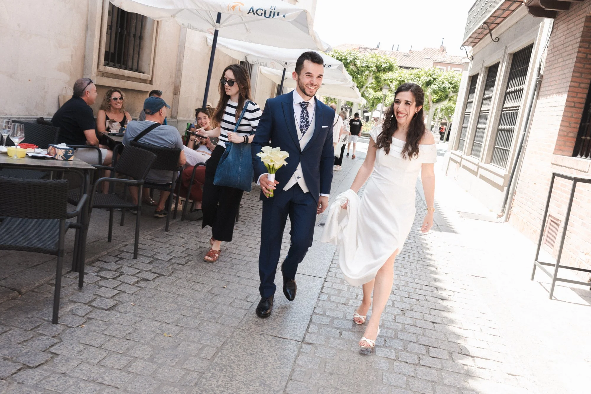 Pareja en su boda caminando entre terrazas de bares en una calle de Madrid