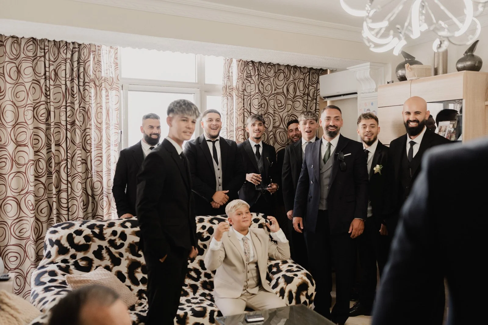 amigos del novio con traje viéndole aparecer en el interior de un salón