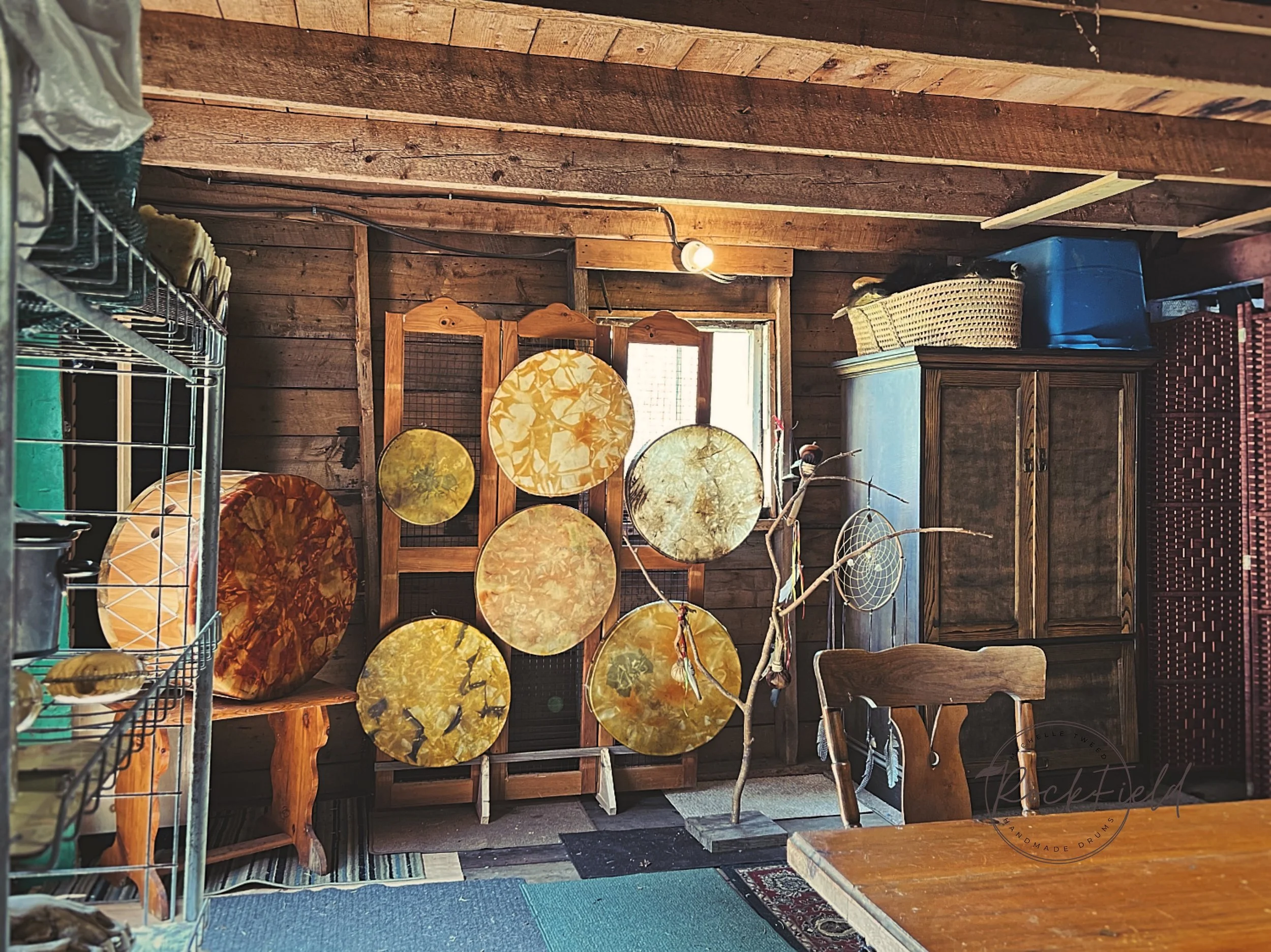 Interior of rustic room with handmade drums, wooden furniture, wire shelving, cozy decor.