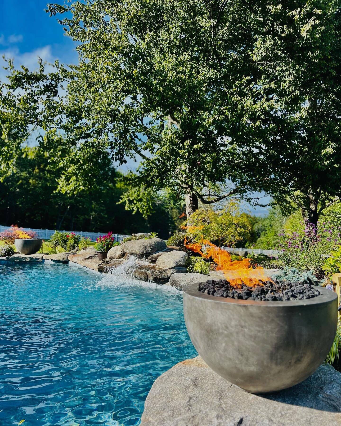 Natural stone pool coping creates the bridge for the water and fire features for this private backyard landscape