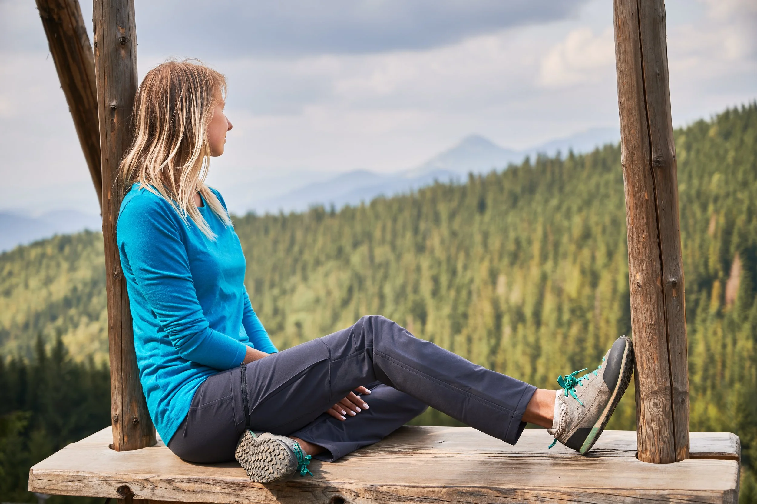 Woman sitting alone looking at the mountains, taking a pause from midlife burnout and brain fog