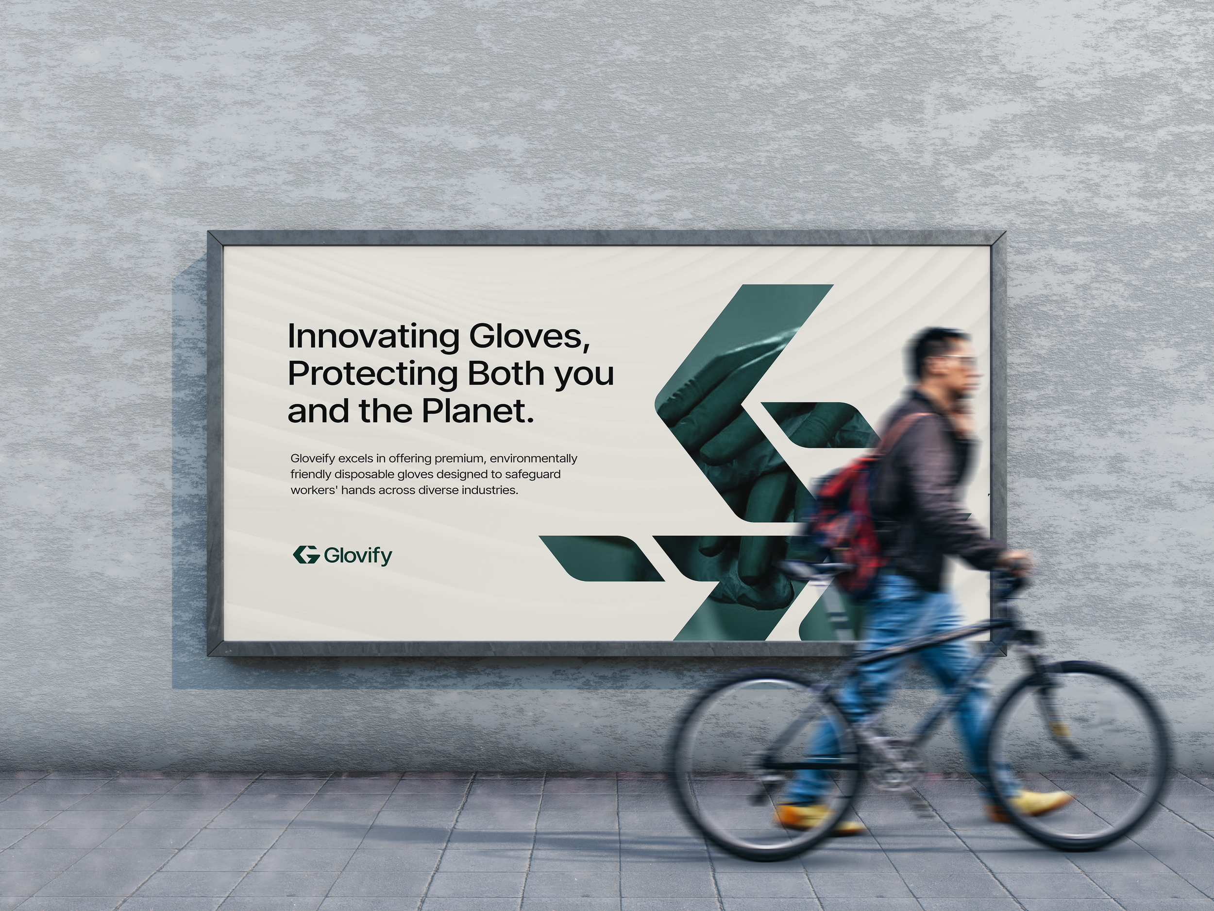 A person riding a bicycle past a billboard on a concrete wall. The billboard advertises gloves with the message, 'Innovating Gloves, Protecting Both you and the Planet,' and features an image of a green glove.