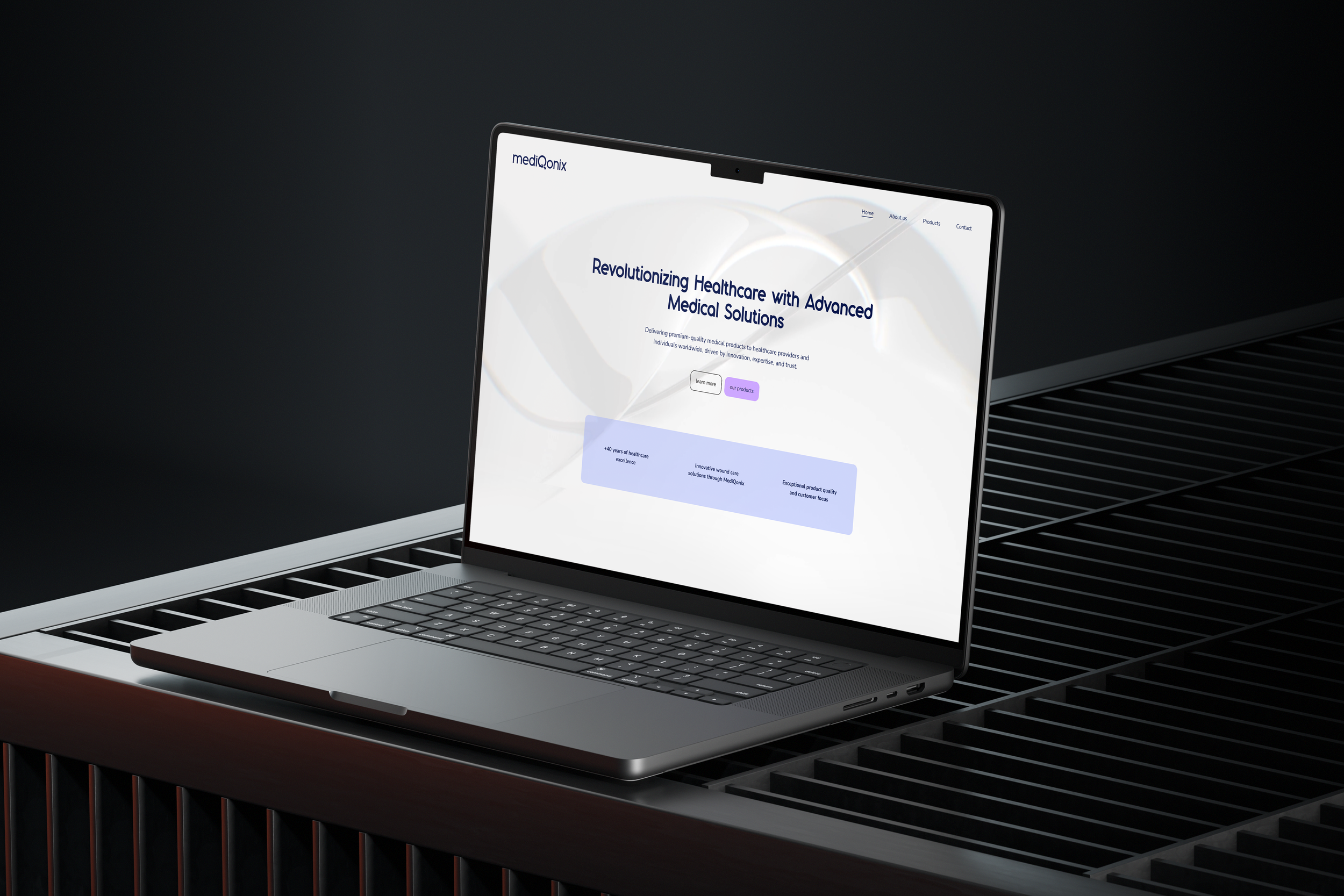 A laptop on a black metal grill surface displaying a healthcare website with a white background and blue text.