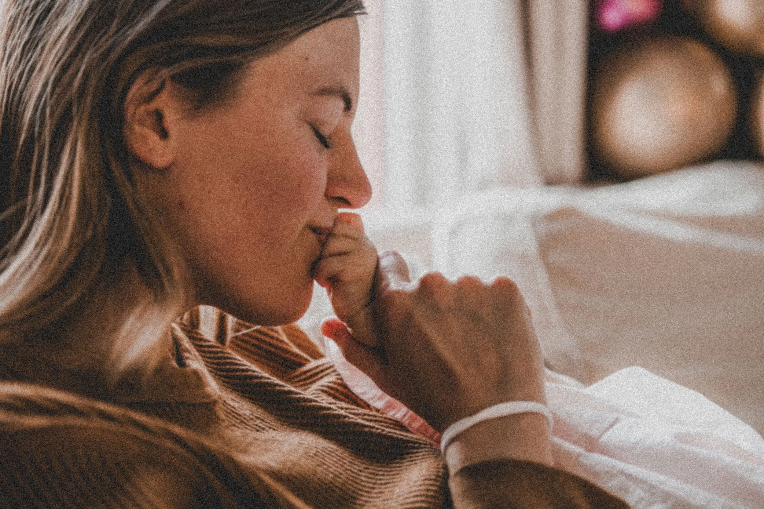 Woman in a hospital bed with a wristband, eyes closed, praying or reflecting, in a peaceful and emotional moment.
