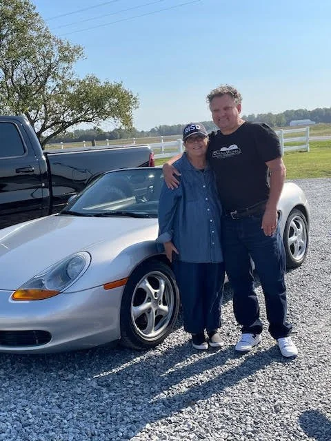 Steve and Julie posing with their 1997 Porsche Boxster 986.