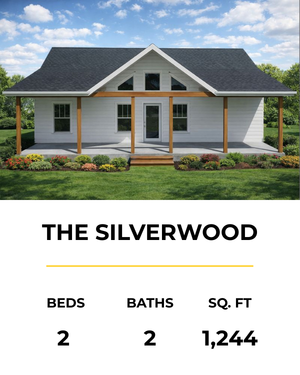 A white house with a gable roof, front porch, and garden surrounded by green grass and trees under a partly cloudy sky.