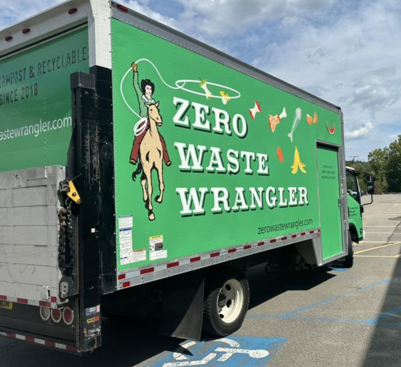 Green waste management truck with a logo showing a woman riding a horse with long black hair and a ponytail, holding a stick. The truck has the text 'ZERO WASTE WRANGLER' and a website link 'zerowastewrangler.com' on the side.