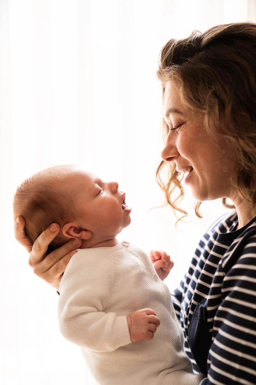 Newborn shoot - Een vrouw houdt haar baby vast en kijkt liefdevol naar de kleine baby.