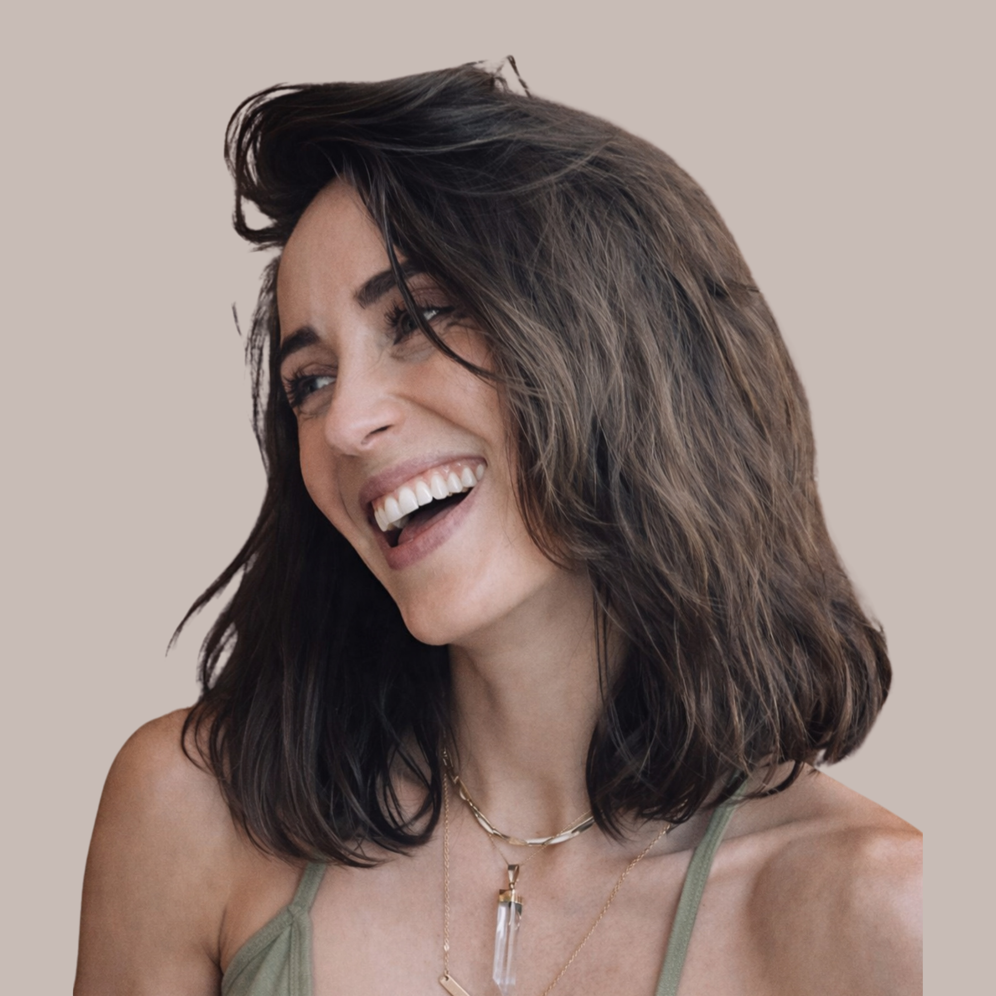 Close-up of a woman with dark brown and black layered hair smiling, wearing a green tank top, layered necklaces, and a confident expression.
