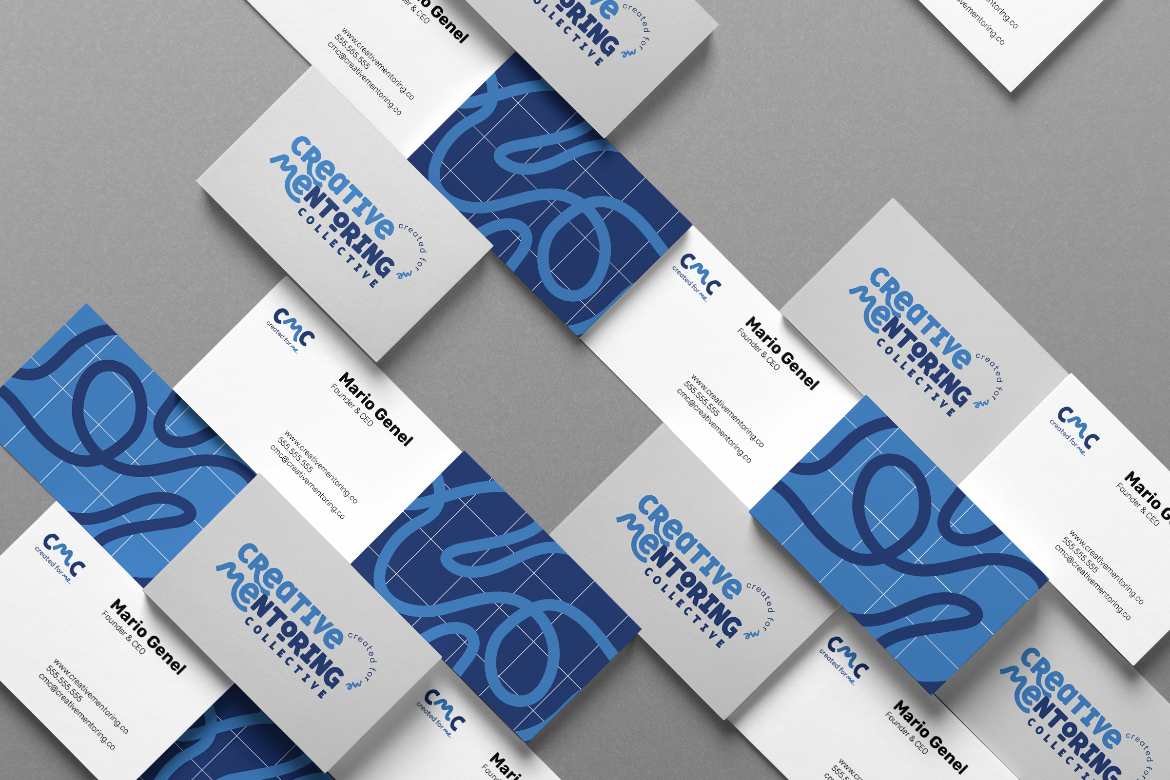 Business cards for Creative Mentoring Collective arranged on a gray surface, with blue and white designs, including text for Mario Genel and contact information.
