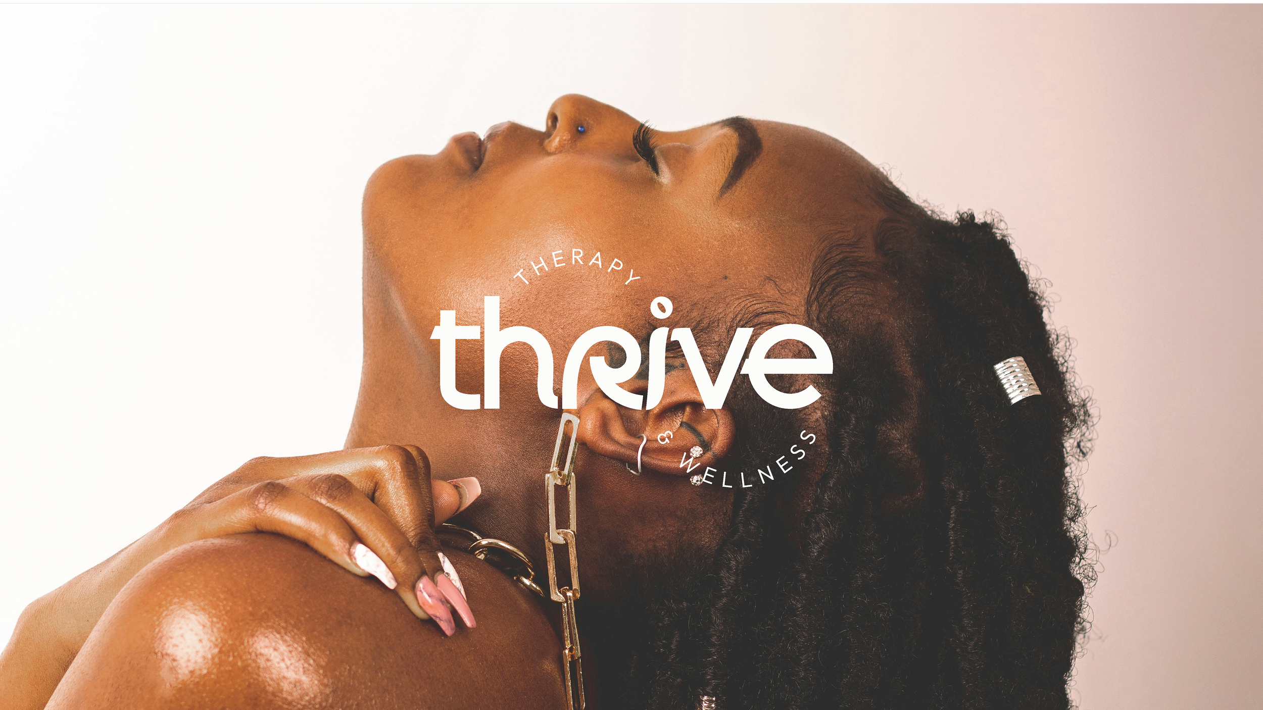 A woman with dark curly hair, closed eyes, and gold jewelry, resting her head back against a white background, with the words "Therapy Thrive Wellness" overlayed.