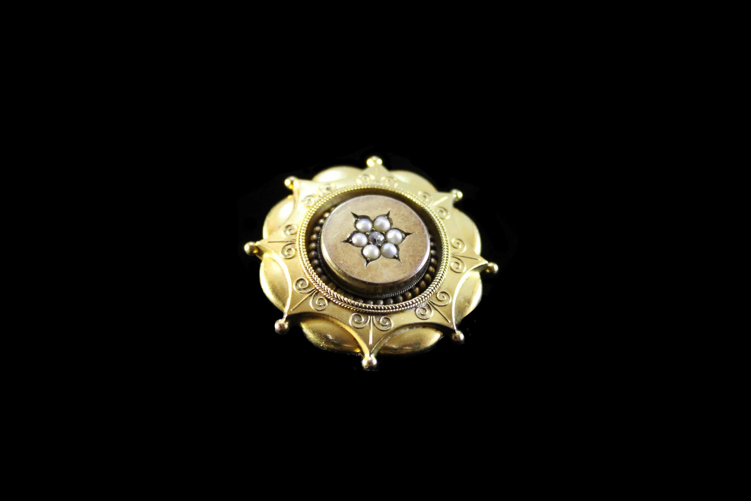 Angled view of Victorian mourning pendant highlighting seed pearl border and central diamond