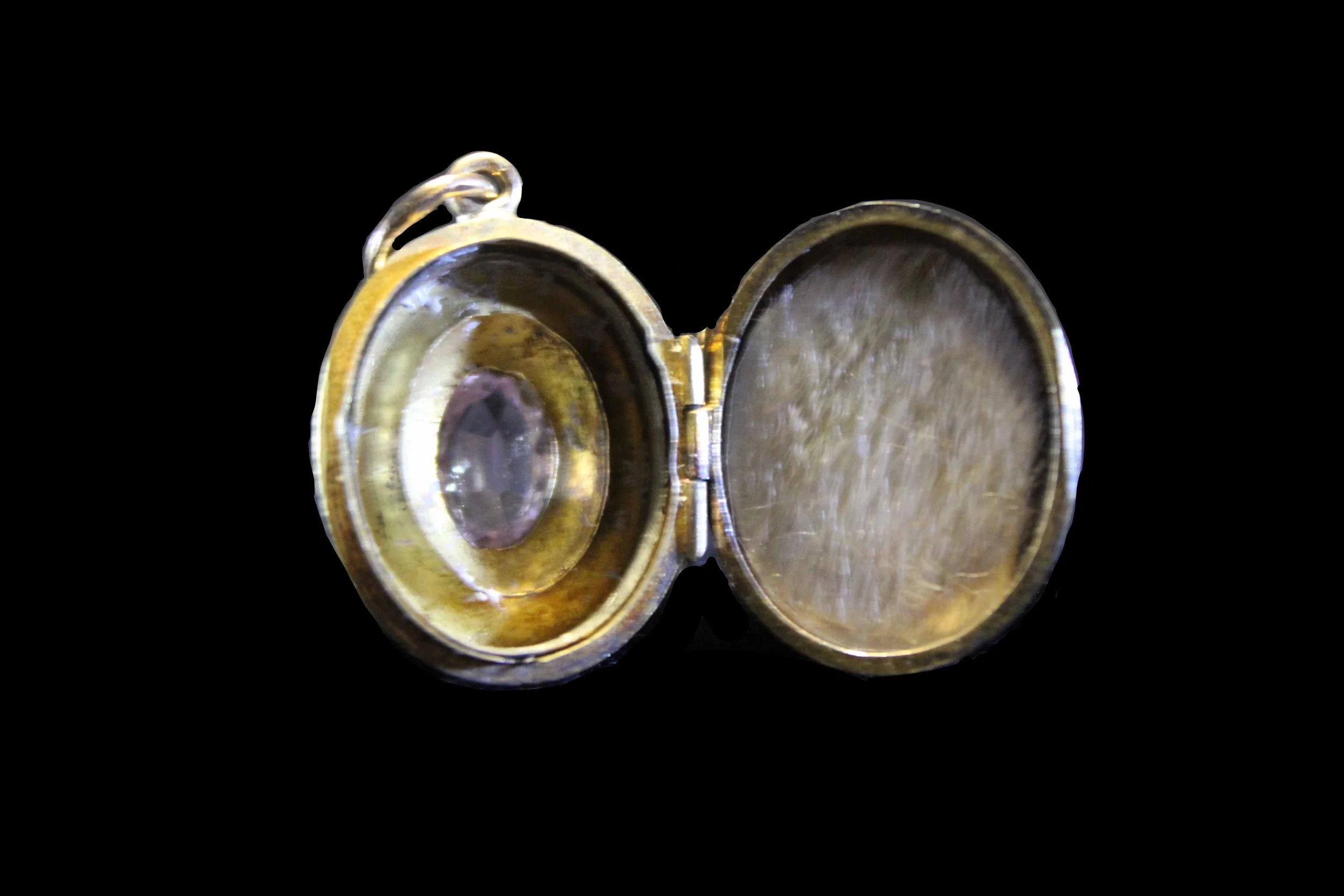 Interior of Victorian gold locket opened to reveal gemstone-backed compartment and original lining