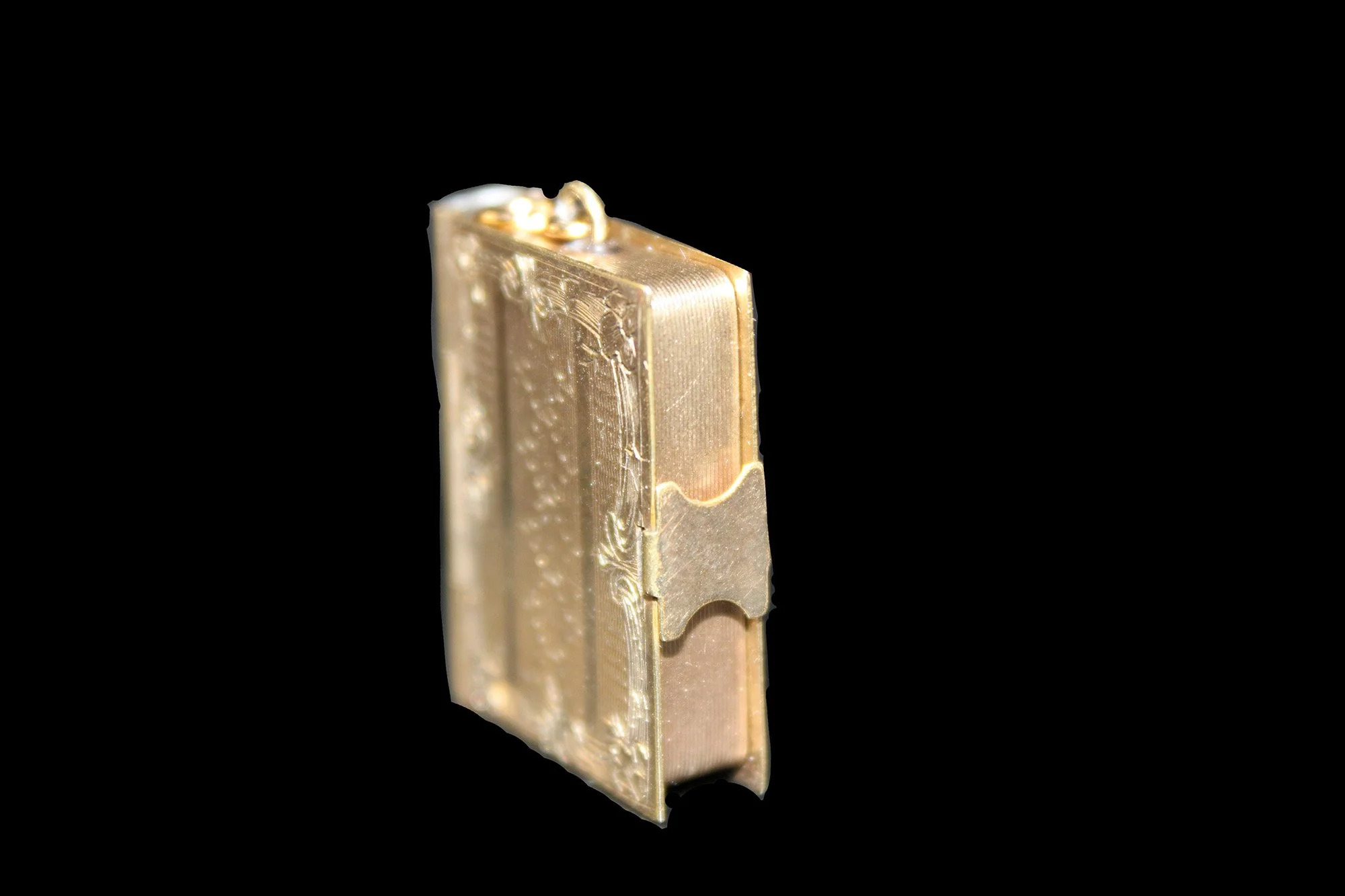 Front cover of Victorian miniature gold book locket with engraved decorative binding.